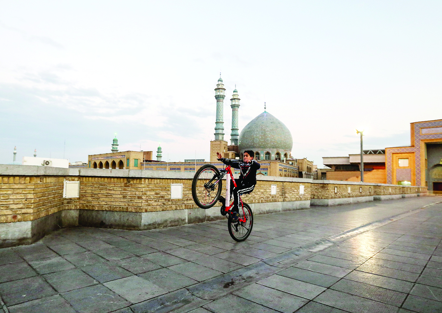 (FILES) This file photo taken on January 14, 2019 shows a child rides his bicycle near the Fatima Masumeh shrine in the holy city of Qom, about 130 kilometres south of the capital Tehran. - Iran closed four key Shiite pilgrimage sites across the Islamic republic on Monday in line with measures to stop the spread of the new coronavirus, state media reported. (Photo by ATTA KENARE / AFP)
