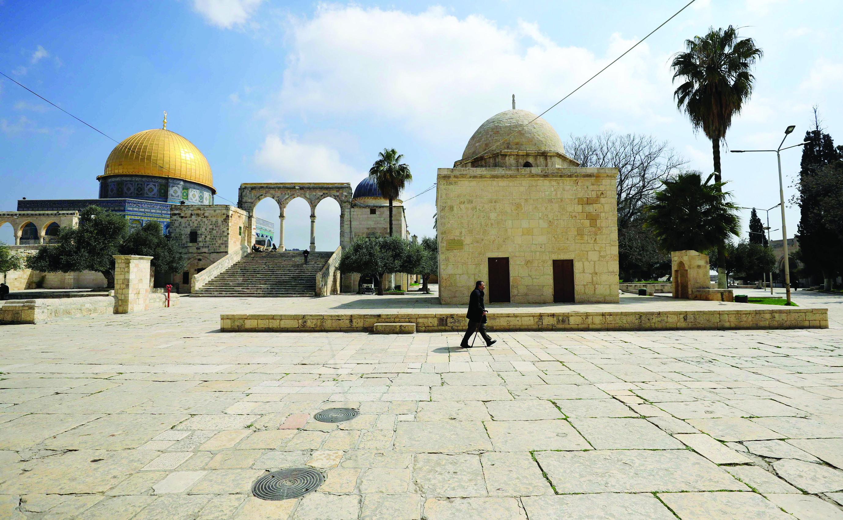 A man walks past the Dome of the Rock, at the al-Aqsa mosque compound, in the Old City of Jerusalem on March 16, 2020. - Israel imposed a two-week quarantine on all travellers entering the country, almost stopping tourism and limiting public gatherings in response to the COVID-19 coronavirus disease. (Photo by Emmanuel DUNAND / AFP)