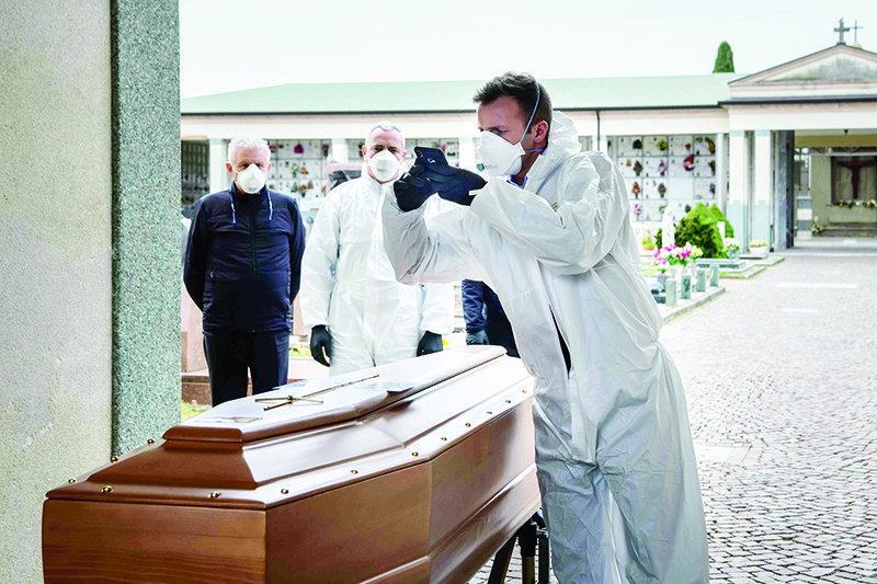 TOPSHOT - This picture taken on March 23, 2020 shows a pallbearer taking a picture of a coffin for the relatives of a deceased person at the cemetery of Grassobbio in the province of Bergamo, as they could not attend the ceremony because they are in quarantine as a result of the COVID-19 novel coronavirus. (Photo by Piero CRUCIATTI / AFP)