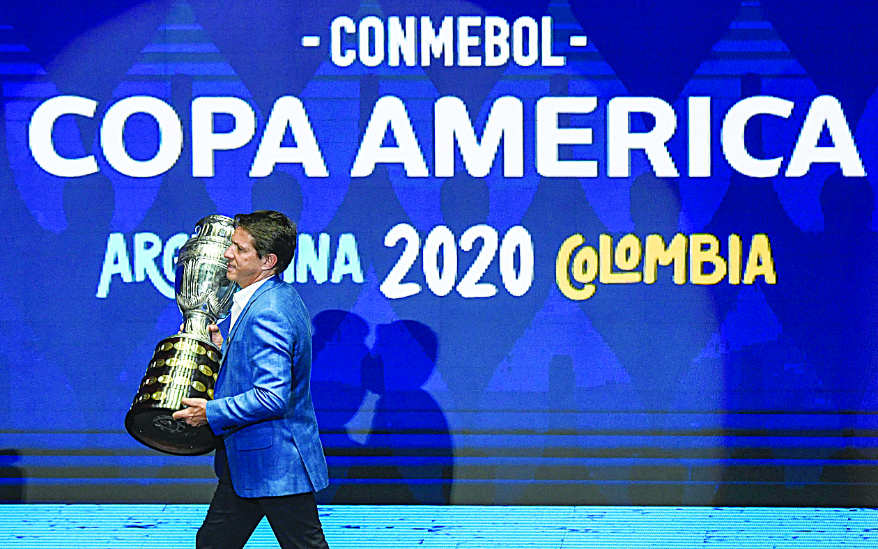 (FILES) In this file picture taken on December 3, 2019 Brazilian former footballer Juninho Paulista presents the Copa America trophy on the stage during the draw of the Copa America 2020 football tournament at the Convention Centre in Cartagena, Colombia - The 2020 Copa America in Argentina and Colombia was postponed on March 17, 2020 by a year to 2021 because of the coronavirus pandemic, organisers CONMEBOL said. The Copa, South America's main men's continental competition, was scheduled to run between June 11-July 11, and for the first time in two countries, featuring 12 teams including invitees Australia and Qatar. (Photo by Juan BARRETO / AFP)