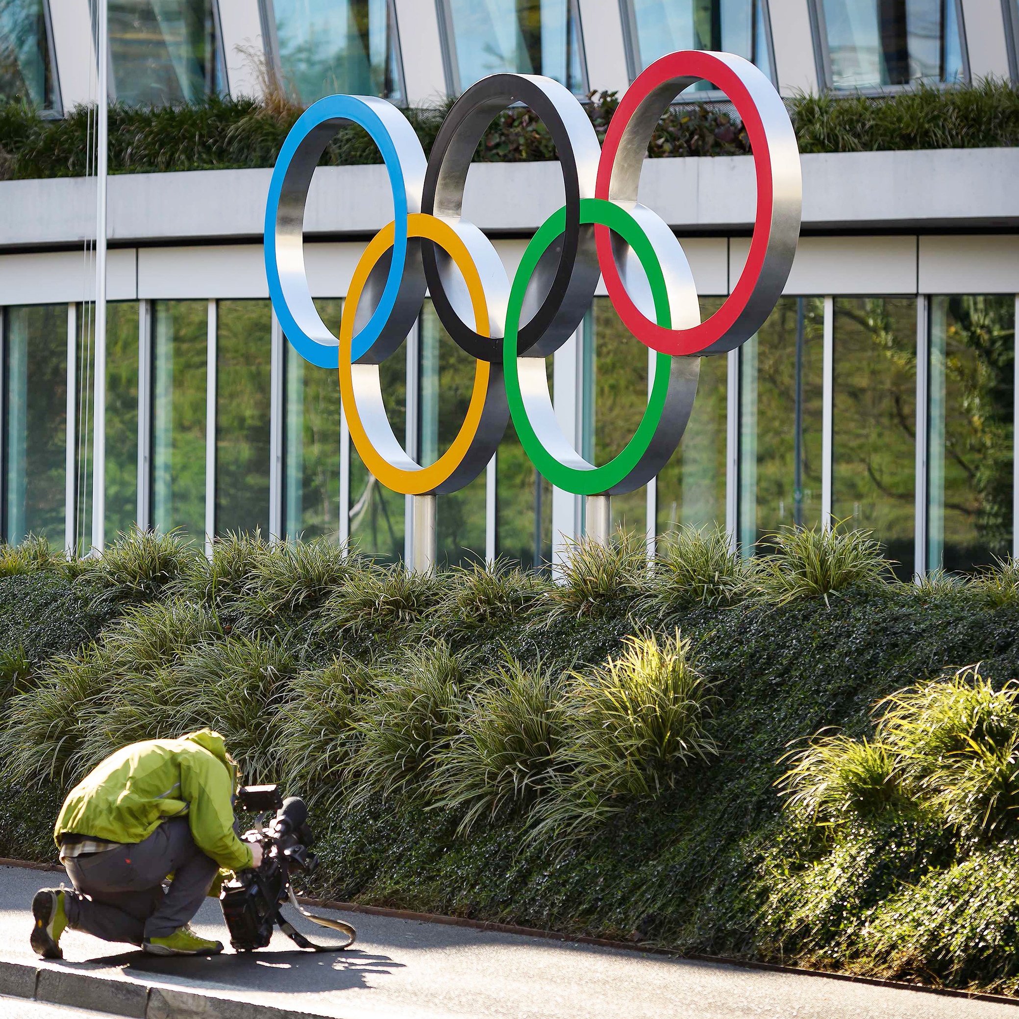 A cameraman films the Olympic Rings at the International Olympic Committee (IOC) headquarters in Lausanne on March 3, 2020. - The COVID-19 which has already killed more than 3000 people in the World will be at the center of a meeting of the International Olympic Committee (IOC) on March 3 and 4, 2020 in Lausanne less than five months before the opening ceremony of the Olympics in Tokyo. (Photo by Fabrice COFFRINI / AFP)