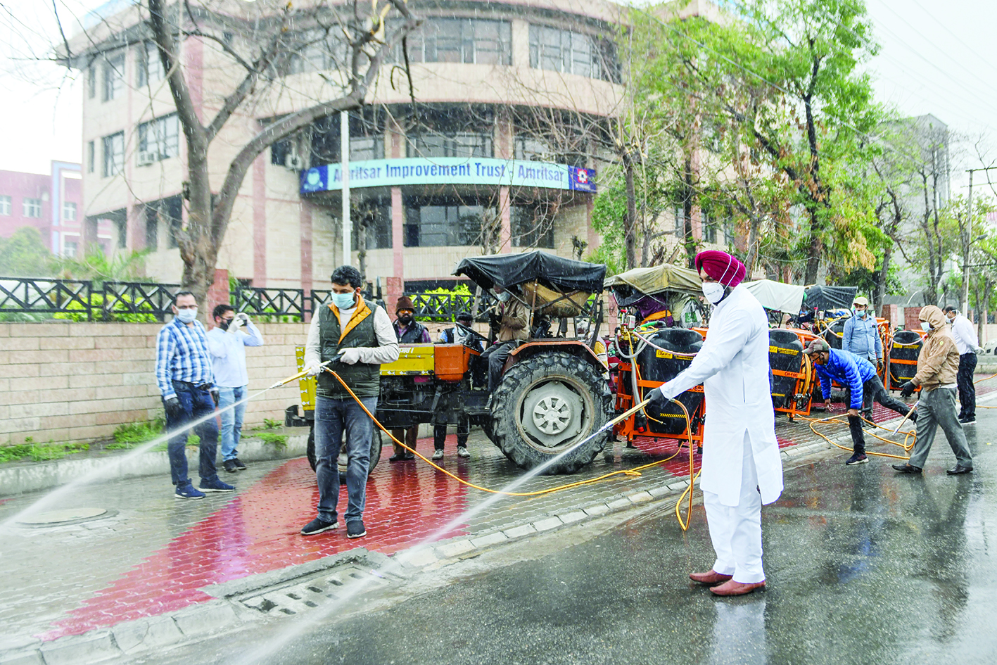 Member of Parliament (MP) Gurjeet Singh Aujla (C-R) and Amritsar Improvement Trust Chairman Dinesh Bassi (C-L) clean a street during a government-imposed nationwide lockdown as a preventive measure against the COVID-19 coronavirus, outside Amritsar Improvement Trust in Amritsar on March 27, 2020. (Photo by NARINDER NANU / AFP)