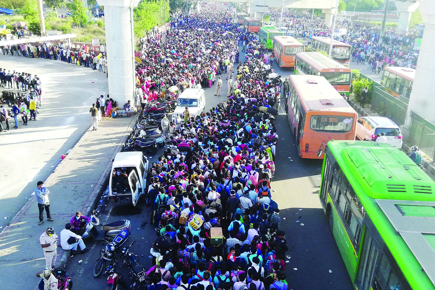 Migrant workers and their family members lineup outsdie the Anand Vihar bus terminal to leave for their villages during a government-imposed nationwide lockdown as a preventive measure against the COVID-19 coronavirus in New Delhi on March 28, 2020. - Tens of thousands of migrant workers and their famiies on March 28 fought and shoved their way onto buses organised by India's most populous state to get them to their home towns amid the coronavirus pandemic. (Photo by Bhuvan BAGGA / AFP)