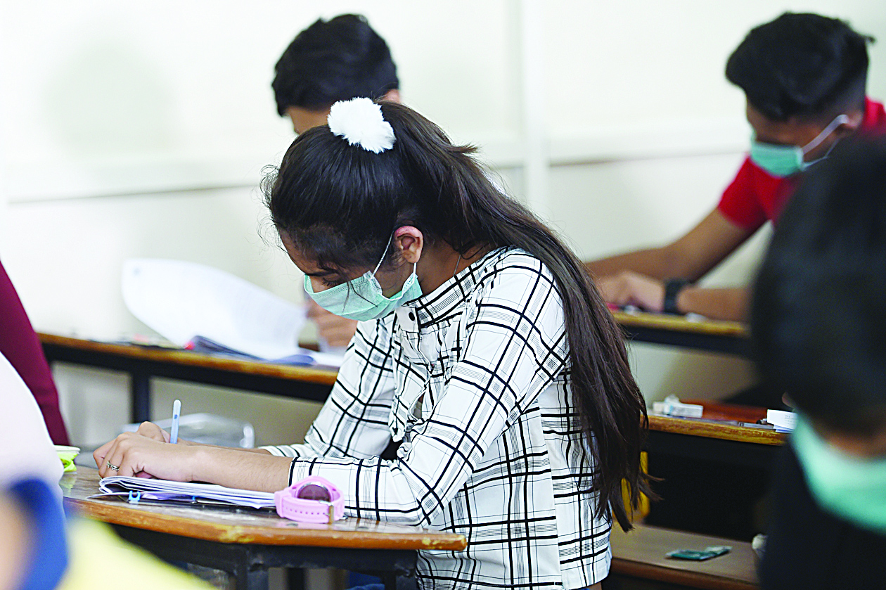 Students sit for the Gujarat Board Xth examination as they wear facemasks provided by the school management at Sadhana Vinay Mandir school, following the COVID-19 coronavirus outbreak, in Ahmedabad on March 5, 2020. - More than 95,000 people have been infected and over 3,200 have died worldwide from the new coronavirus, which by on March 5 had reached some 80 countries and territories. (Photo by SAM PANTHAKY / AFP)