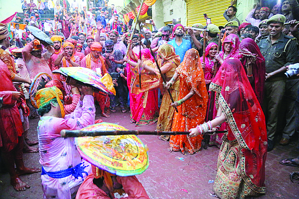 Women beat men with sticks during the Lathmar Holi celebration in the village of Barsana on the outskirts of Mathura in the northern Indian state of Uttar Pradesh on March 4, 2020. - Lathmar Holi is a local celebration of the Hindu festival of Holi, usually some days ahead of the Holi festival which is a spring festival, also called 'festival of colours' observed in India at the end of winter season. (Photo by STR / AFP)