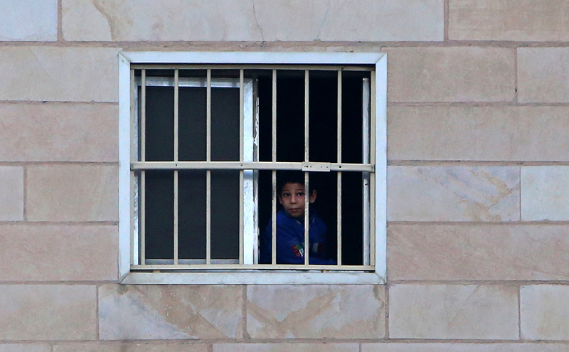 A boy looks on from the window of a flat in a building in Kuwait City on April 2, 2020, during a government-imposed curfew as a measure against the COVID-19 coronavirus pandemic. (Photo by YASSER AL-ZAYYAT / AFP)
