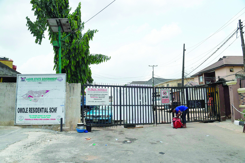 A man searches in a bag for his clearance document at the main gate to Omole Estate, whose occupants were attacked by armed bandits capitalising on the lockdown in Lagos, on April 14, 2020. - Nigerian President Muhammadu Buhari on April 13, 2020, ordered a two-week extension to a lockdown in largest city Lagos, neighbouring Ogun state and capital Abuja, aimed at halting the spread of the COVID-19 coronavirus. (Photo by PIUS UTOMI EKPEI / AFP)