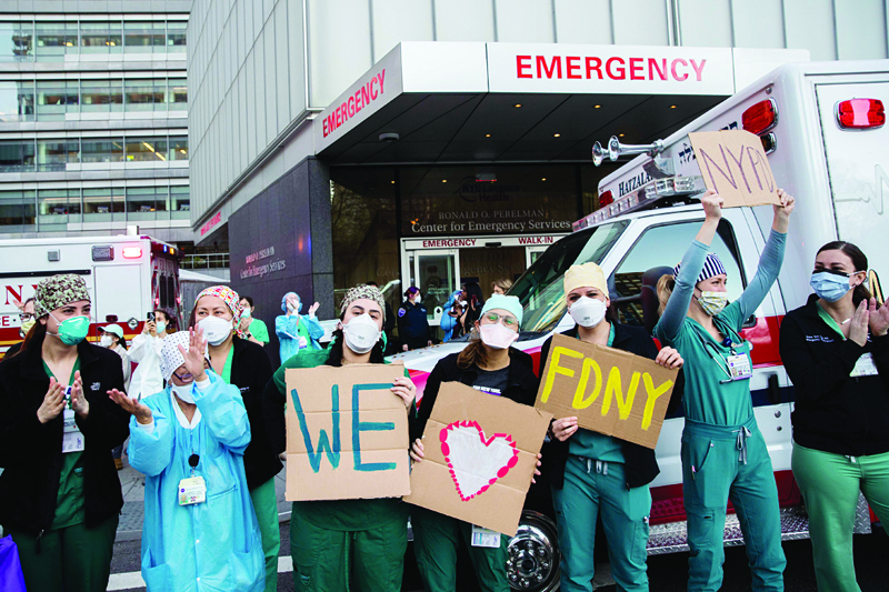 NEW YORK, NY - APRIL 21: Medical workers hold signs outside NYU Langone Health hospital as people applaud to show their appreciation to medical staff and essential workers on the front lines of the coronavirus pandemic on April 21, 2020 in New York City. COVID-19 statistics continue to trend downward in the tri-state region, but New York City has surpassed 132,000 cases since the outbreak.   Jeenah Moon/Getty Images/AFPn== FOR NEWSPAPERS, INTERNET, TELCOS &amp; TELEVISION USE ONLY ==