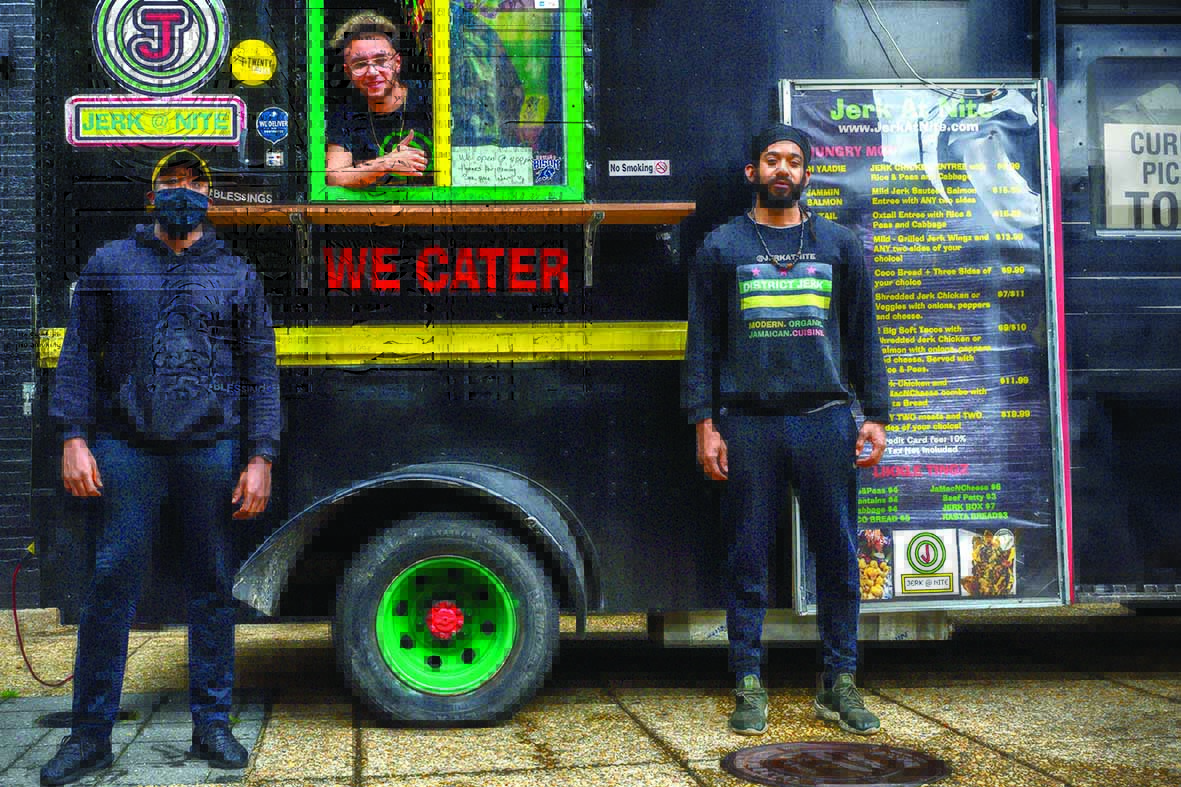 Jerk@Nite food truck owners Kareem Todd (L) and Denville Myrie pose by their food truck parked in front of their newly acquired brick and mortar restaurant on April 24, 2020 in Washington DC. - The coronavirus epidemic has emptied downtown Washington and the food- trucks clustered near squares or the National Mall have disappeared. In order to survive, the trucks are migrating to the neighborhoods where potential  clients are confined. (Photo by Eric BARADAT / AFP)