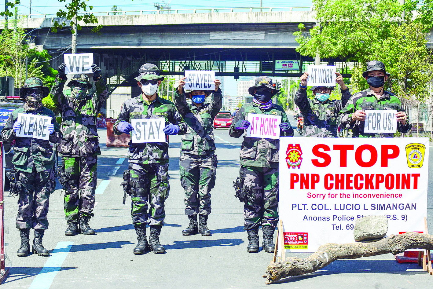 Police personnel hold up placards reminding people to stay at home amid concerns of the spread of the COVID-19 coronavirus in Manila on March 31, 2020. - The main Philippine island of Luzon, home to 55 million people which includes the capital Manila, is in the second week of a lockdown to contain the spread of the disease. (Photo by Maria TAN / AFP)