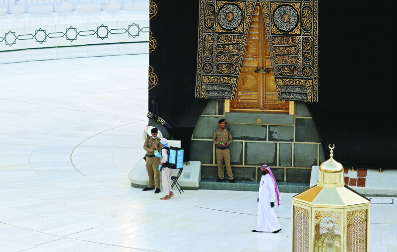 A picture taken on April 24, 2020, shows Saudi policemen standing guard next to the Kaaba in Mecca's Grand Mosque, on the first day of the Islamic holy month of Ramadan, amid unprecedented bans on family gatherings and mass prayers due to the coronavirus (COVID-19) pandemic. (Photo by STR / AFP)