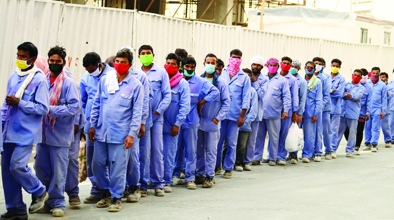 Foreign workers wearing scarves to protect their faces, stand in line to board a bus transporting them to their workplace, during the novel coronavirus pandemic crisis, in the Emirati city of Dubai, on April 2, 2020. (Photo by KARIM SAHIB / AFP)
