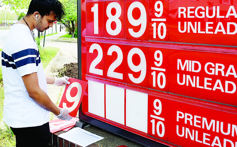 (FILES) In this file photo taken on April 21, 2020, an employee of a gas station in Arlington, Virginia, adjusts gasoline pump prices as they continue to fall. - Beaten-down US oil prices rallied on April 22, 2020, following dramatic declines earlier this week even as American crude inventories near capacity levels. Futures for the benchmark West Texas Intermediate for June delivery jumped 19 percent to $13.78 a barrel in New York. (Photo by Olivier DOULIERY / AFP)