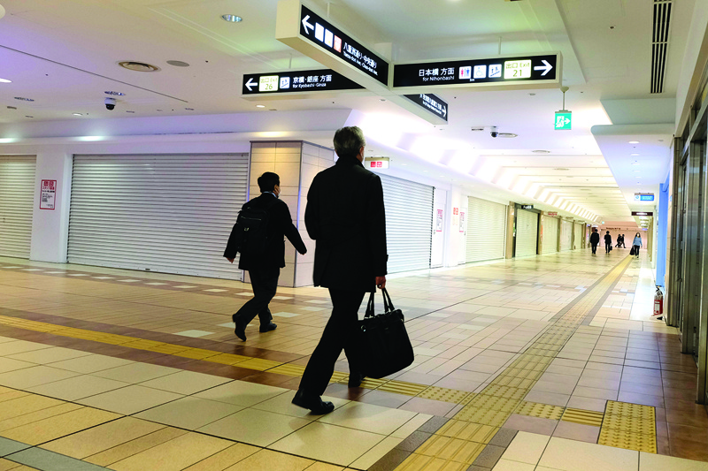 Commuters walk past closed shops in an underground shopping mall in Tokyo railway station on April 15, 2020. (Photo by Kazuhiro NOGI / AFP)