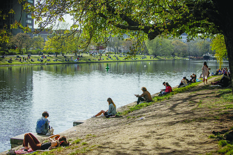 People sit on the banks of the Landwehr canal in Berlin's Kreuzberg district as the sun shines on April 11, 2020 amid the novel coronavirus COVID-19 pandemic. (Photo by David GANNON / AFP)