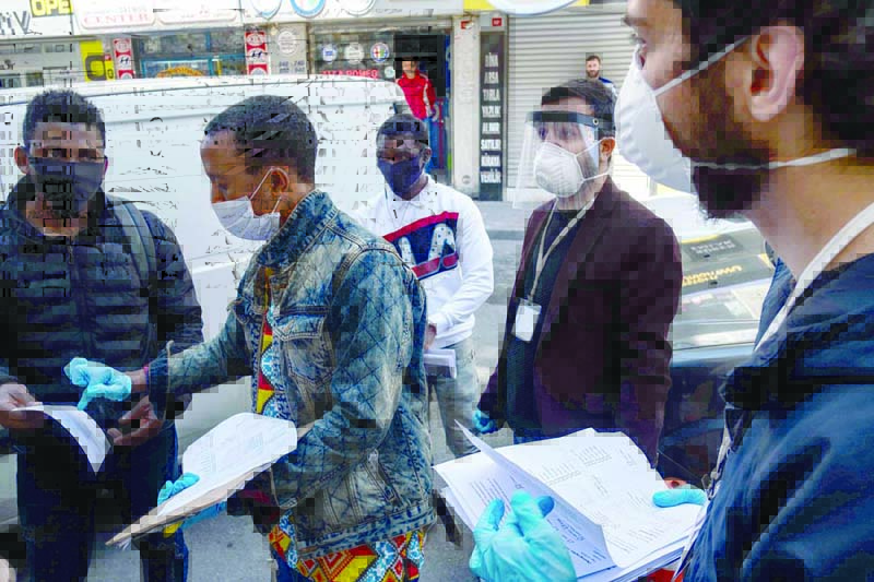 Members of a solidarity network hand out disinfectant, gloves and face masks as well as food cards to African migrants in Istanbul on April 17, 2020, during the COVID-19 pandemic, caused by the novel coronavirus. - Istanbul's African migrants are among the most vulnerable groups as the coronavirus pandemic hits Turkey's largest city. Some 80,000 -- most of them undocumented-- live in the city of about 15 million people where almost half of the nearly 80,000 coronavirus cases have been recorded. (Photo by Yasin AKGUL / AFP)