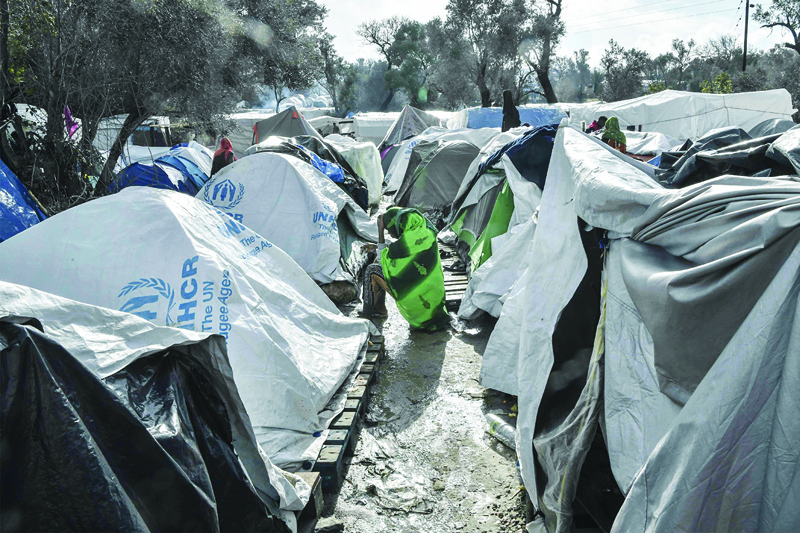 (FILES) In this file photo taken on December 11, 2019, A Somali woman sits outside her tent in the Vial camp on the island of Chios which has only 1,000 places, but houses nearly 5,000 asylum seekers in unsanitary conditions and many camps  situated in the nearby olive groove are without toilets, bathrooms, electricity and water. - A fire ripped through one of Greece's largest migrant camps leaving widespread damage and many people homeless after the death of an Iraqi woman sparked unrest, officials said on April 19, 2020. The blaze late April 18, at Vial camp on Chios island destroyed the facilities of the European asylum service, a camp canteen, warehouse tents and many housing containers, Migration Ministry Secretary Manos Logothetis told AFP. (Photo by LOUISA GOULIAMAKI / AFP)