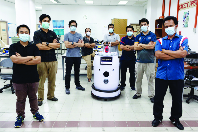Engineering professors pose with the version two prototype of the IIUM Medibot medical robot, being developed for health workers to treat patients without risking infection from the COVID-19 coronavirus, at the International Islamic University Malaysia in Gombak, on the outskirts of Kuala Lumpur, on April 13, 2020. (Photo by Mohd RASFAN / AFP)
