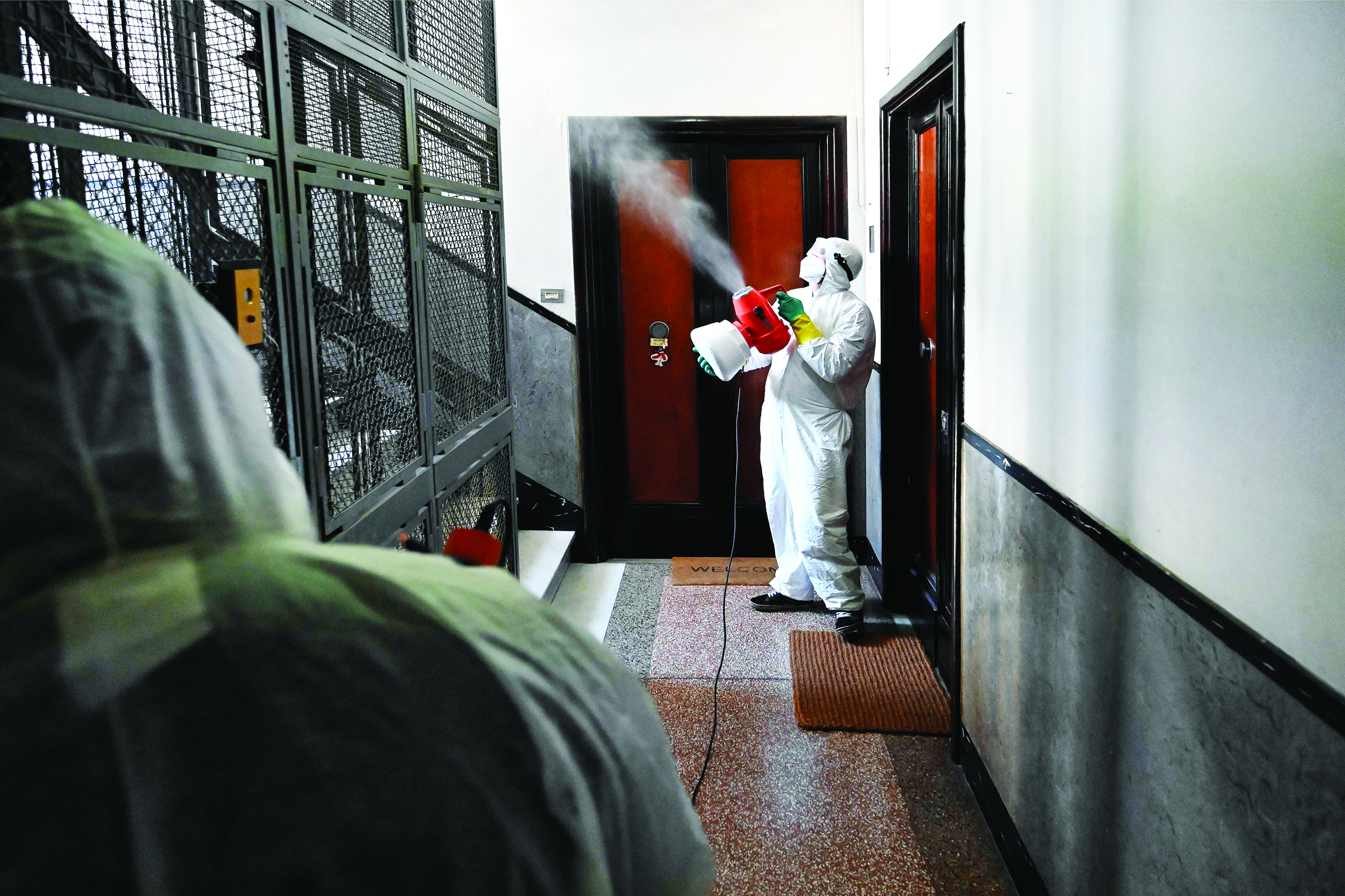 TOPSHOT - Employees of a private company spray disinfectant in a building on March 31, 2020 in Rome, during the country's lockdown aimed at stopping the spread of the COVID-19 (new coronavirus) pandemic. (Photo by Alberto PIZZOLI / AFP)