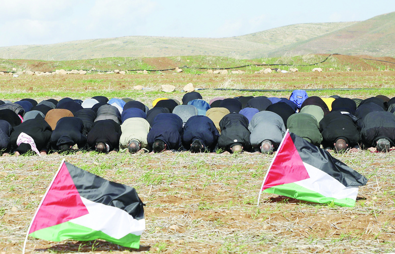 (FILES) In this file photo taken on January 31, 2020 Palestinian protesters perform the Friday prayer behind national flags during a protest against a US brokered Middle East peace plan, outside the West Bank village of Tamun near the Jordan Valley, on January 31, 2020. - Arab foreign ministers are to hold talks on April 30, 2020 on Israel's US-backed plans to annex key parts of the occupied West Bank. Concern has mounted since Israel's right-wing Prime Minister Benjamin Netanyahu -- an outspoken advocate of annexing large parts of the Palestinian territory -- agreed to form a coalition with his centrist rival Benny Gantz. (Photo by JAAFAR ASHTIYEH / AFP)