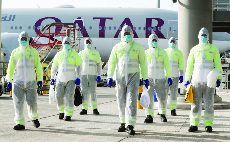 (FILES) In this file photo taken on April 01, 2020, employees of Qatar Aviation Services (QAS), wearing protective gear as a safety measure during the COVID-19 coronavirus pandemic, walk along the tarmac after sanitising an aircraft at Hamad International Airport in the Qatari capital Doha. - Qatar has seen its airline's crews applauded and won thumbs-up from governments after repatriating thousands of travellers stranded by the coronavirus aviation shutdown. Observers say Doha is hoping that by keeping its planes in the skies, in contrast to its regional competitors, it will win diplomatic points (Photo by KARIM JAAFAR / AFP)