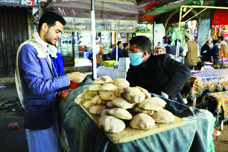A man, wearing a protective mask and gloves amid the coronavirus (COVID-19) pandemic, sells bread at his stall in the old city market of the capital Sanaa, late on April 10, 2020. - Yemen reported its first case of coronavirus in a southern government-controlled province, raising fears of an outbreak in the war-torn country as air strikes blamed on the Saudi-led coalition tested a unilateral truce. (Photo by MOHAMMED HUWAIS / AFP)