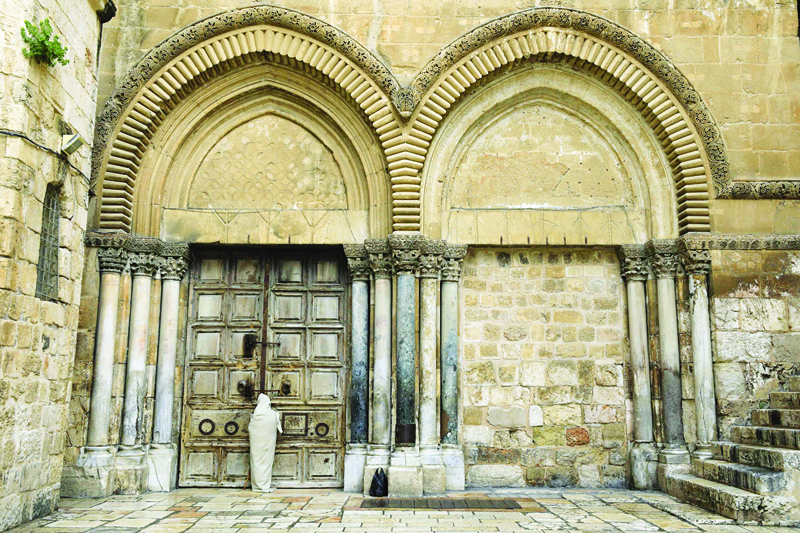 TOPSHOT - A Christian pilgrim dressed as Jesus Christ stands in front of the closed door of the Holy Sepulchre Church in Jerusalem's Old City on April 10, 2020, marking Good Friday, amid the COVID-19 pandemic crisis. - All cultural sites in the Holy Land are shuttered, regardless of their religious affiliation, as authorities seek to forestall the spread of the deadly respiratory disease, which will prevent Christians from congregating for the Easter service, this coming Sunday for Catholic worshippers, then a week later on April 19 for Orthodox Easter. (Photo by EMMANUEL DUNAND / AFP)