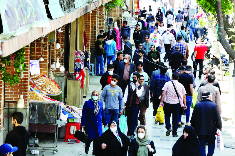Iranians, some wearing protective gear amid the COVID-19 pandemic, shop on a street by the Grand Bazaar market in the capital Tehran, on April 18, 2020. - Iran allowed some shuttered Tehran businesses to reopen on April 18, despite the Middle East's deadliest coronavirus outbreak, as many faced a bitter choice between risking infection and economic ruin. (Photo by ATTA KENARE / AFP)