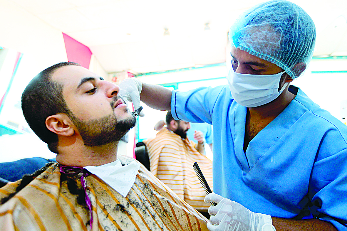 A Yemeni barber cuts a customer's beard while wearing a face mask and gloves amid the COVID-19 coronavirus pandemic, in the Yemeni capital Sanaa on April 4, 2020. (Photo by Mohammed HUWAIS / AFP)