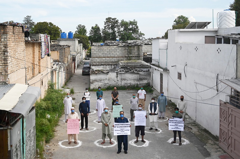 Local residents wearing facemasks and practicing social distancing hold placards as they protest against quarantine facility center set up in their neighborhood during a government-imposed nationwide lockdown as a preventive measure against the COVID-19 coronavirus, in Islamabad on April 19, 2020. (Photo by Aamir QURESHI / AFP)
