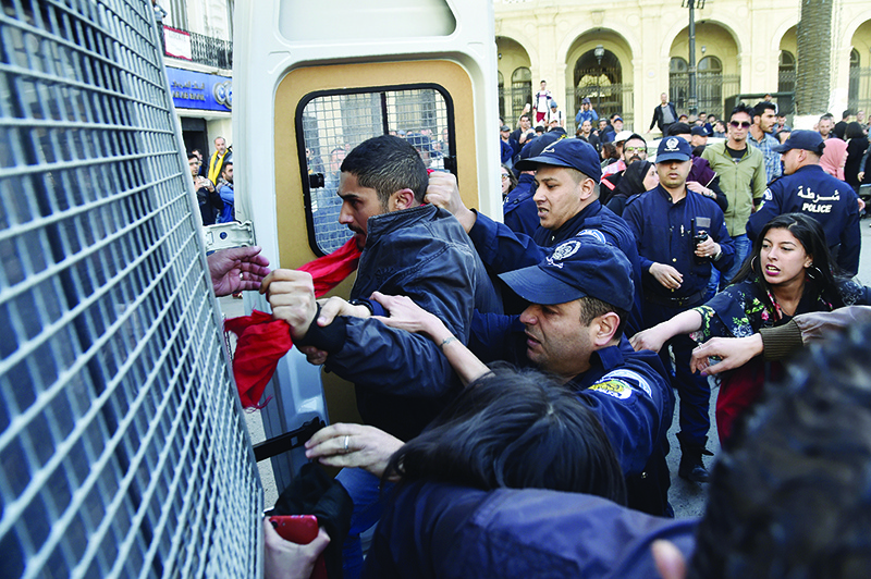 (FILES) In this file photo taken on April 14, 2019, Algerian policemen detain protesters after they demonstrated at Emir Abdelkader square in the capital Algiers. - Dozens of Algerians linked to the country's anti-government protest movement remain in pre-trial detention during the coronavirus crisis, with little or no legal support. (Photo by RYAD KRAMDI / AFP)