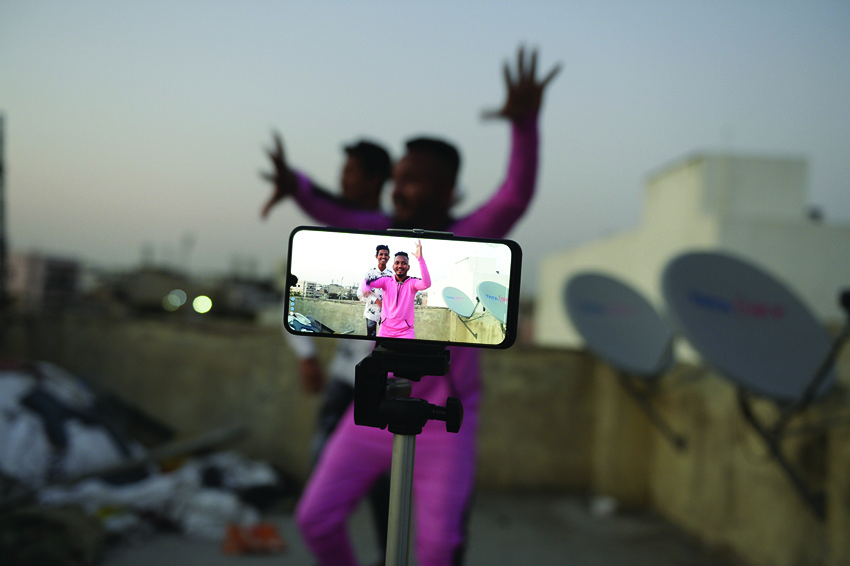 (FILES) In this file photo taken on February 14, 2020 youths act in front of a mobile phone camera while making a TikTok video on the terrace of their residence in Hyderabad. - This is TikTok's time. The social video platform which was already a favorite of teens is increasingly being used by adults looking for ways to pass the time during coronavirus lockdowns. (Photo by NOAH SEELAM / AFP)