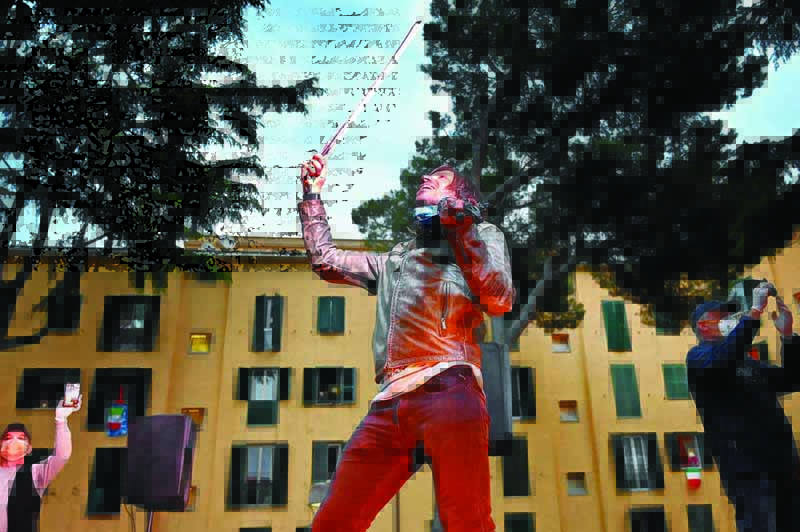 Electric violonist Andrea Casta (C) performs in the courtyard of a popular apartment building for the show Sotto lo Stesso Cielo tour (Under the same sky tour) in San Basilio suburbs of Rome on April 18, 2020, during the country's lockdown aimed at stopping the spread of the COVID-19 (new coronavirus) pandemic. (Photo by Alberto PIZZOLI / AFP)