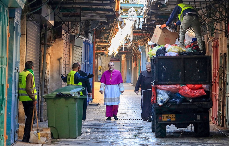 JERUSALEM: Archbishop Pierbattista Pizzaballa, Apostolic Administrator of the Latin Patriarchate of Jerusalem, walks past garbage collectors yesterday as he makes his way to the Church of the Holy Sepulchre before the start of the Easter Sunday service amid the coronavirus disease outbreak. —  AFP