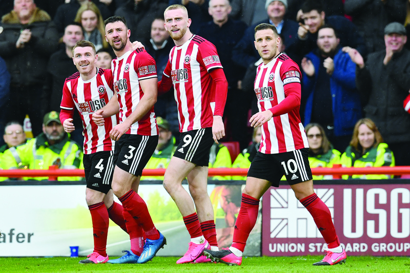 (FILES) In this file photo taken on February 22, 2020 Sheffield United's Irish defender Enda Stevens (2nd L) celebrates with teammates after scoring the opening goal of the English Premier League football match between Sheffield United and Brighton and Hove Albion at Bramall Lane in Sheffield, northern England. - Sheffield United announced on April 21, 2020, that their players will defer part of their wages until the end of 2020 to help the Premier League club ride out the economic storm caused by coronavirus. The Blades manager Chris Wilder, senior members of his coaching staff and chief executive Stephen Bettis have also agreed a wage deferral for six months. (Photo by Paul ELLIS / AFP) / RESTRICTED TO EDITORIAL USE. No use with unauthorized audio, video, data, fixture lists, club/league logos or 'live' services. Online in-match use limited to 120 images. An additional 40 images may be used in extra time. No video emulation. Social media in-match use limited to 120 images. An additional 40 images may be used in extra time. No use in betting publications, games or single club/league/player publications. /