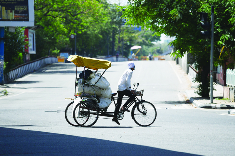 A rickshaw driver carries a load along a deserted road during a government-imposed nationwide lockdown as a preventive measure against the COVID-19 coronavirus, in New Delhi on April 12, 2020. (Photo by Sajjad  HUSSAIN / AFP)