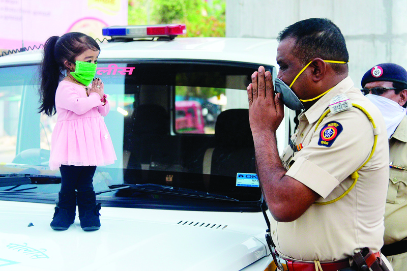TOPSHOT - Guinness world record holder of the world's smallest living woman, Jyoti Amge (L), greets a police officer as she appeals citizens to stay inside their homes during a government-imposed nationwide lockdown as a preventive measure against the COVID-19 coronavirus, in Nagpure on April 13, 2020. (Photo by STR / AFP)