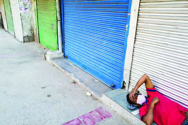 A migrant worker speaks on his mobile phone laying in front of a closed shop in a market area during a government-imposed lockdown as a preventive measure against the spread of the COVID-19 coronavirus in New Delhi on April 21, 2020. (Photo by Jewel SAMAD / AFP)