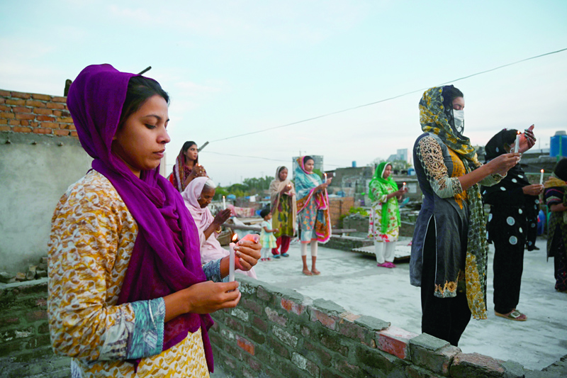 Christians hold candles as they offer prayers during an Easter service in the rooftop of their house during a government-imposed nationwide lockdown as a preventive measure against the COVID-19 coronavirus, in Islamabad on April 12, 2020. (Photo by Aamir QURESHI / AFP)