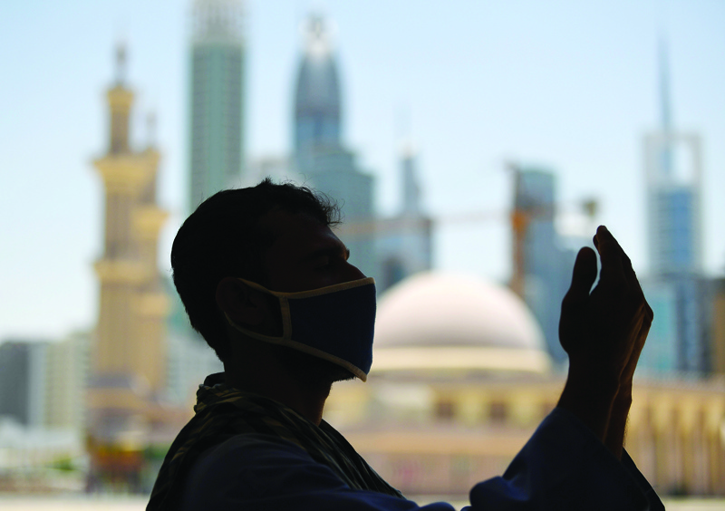 TOPSHOT - A mask-clad Muslim worker prays near a mosque on the first Friday of the holy fasting month of Ramadan, amidst a curfew due to the COVID-19 coronavirus pandemic, in Dubai on April 24, 2020. (Photo by KARIM SAHIB / AFP)