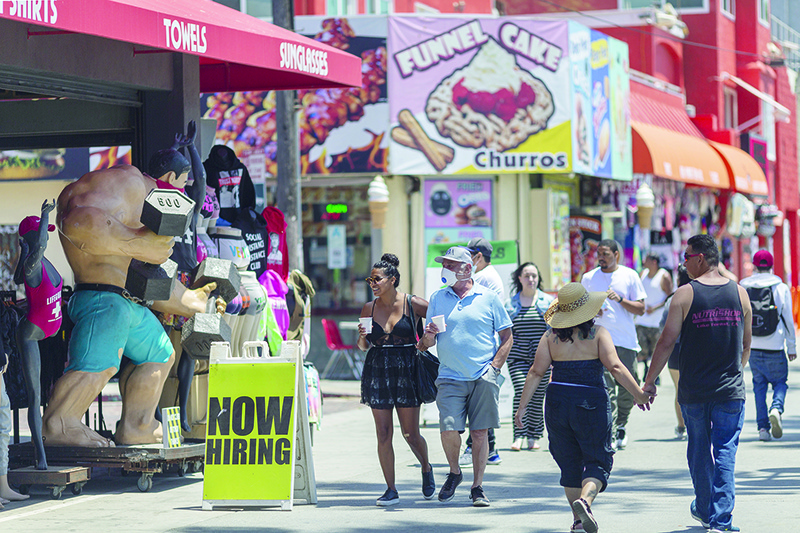 LOS ANGELES, CA: A shop advertises a job opening while holiday beachgoers head to Venice Beach. The number of people filing new claims for state unemployment benefits likely totaled a seasonally adjusted 2.1 million for the week ended May 23, down from 2.438 million the prior week.-- AFP