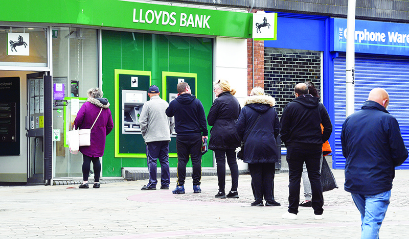 LONDON: People adhere to social distancing guidelines as they queue to enter a Lloyds bank in Barrow-in-Furness, north west England. Bank of England Governor Andrew Bailey said Britain’s economic recovery from the coronavirus pandemic could be “longer and harder” than anticipated and fresh bids to boost growth may be needed. — AFP