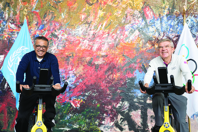 GENEVA: WHO Director-General Tedros Adhanom Ghebreyesus (left) and International Olympic Committee (IOC) president Thomas Bach pose on stationary bicycles prior to signing a cooperation agreement on promoting healthy society through sport and on contributing to the prevention of non-communicable diseases at the WHO headquarters in Geneva. - AFP