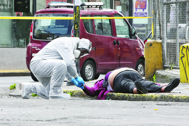 EDITORS NOTE: Graphic content / An Ecuadorian criminalistics police member verifies the death of a woman who died of unknown causes in a street of Quito, on May 14, 2020, amid the new coronavirus pandemic. (Photo by Cristina Vega Rhor / AFP)