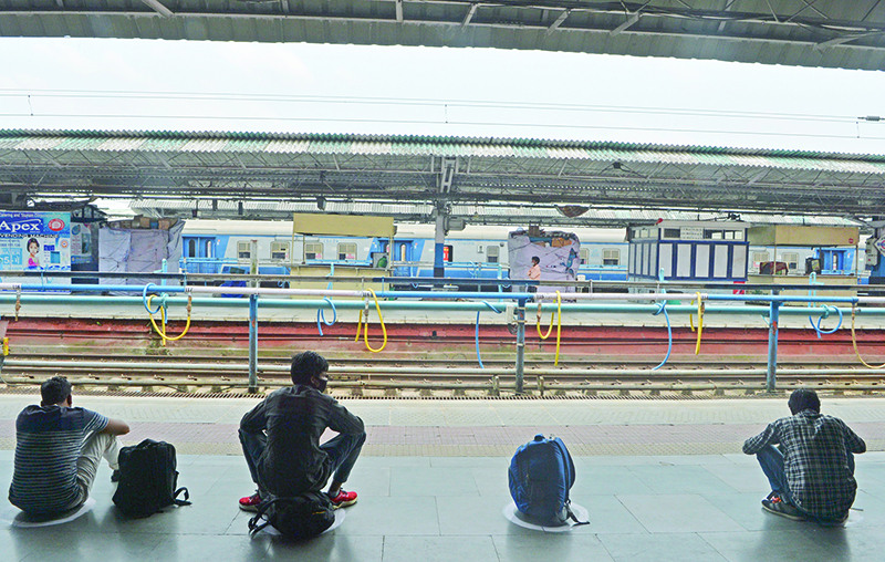 NEW JALPAIGURI: Passengers sit in marked circles to maintain social distancing as they wait for the train to arrive at New Jalpaiguri railway station on the outskirts of Siliguri yesterday. —AFP