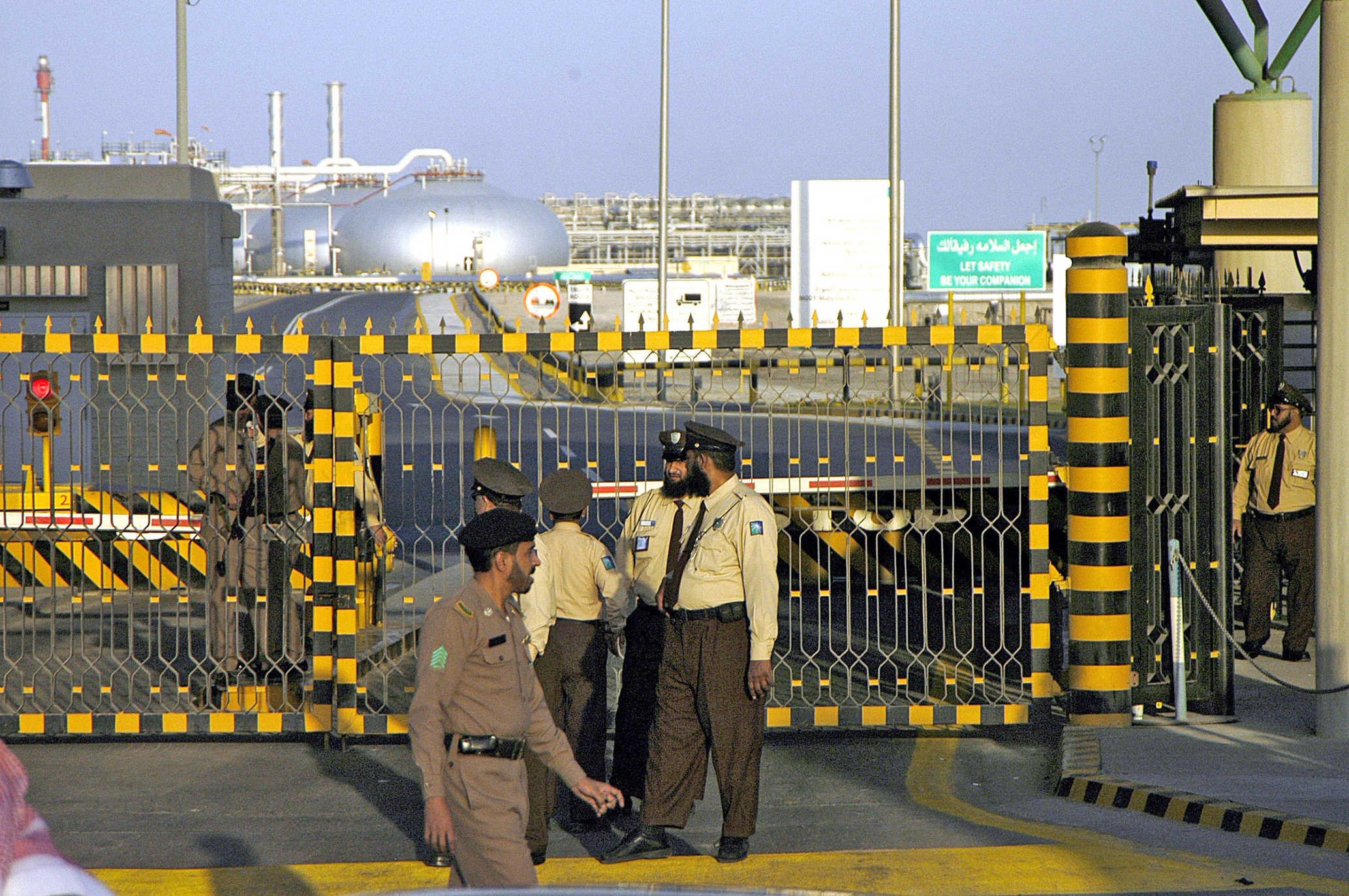 (FILES) In this file photo taken on February 25, 2006, Saudi security men stand at the entrance of the oil processing plant of the state oil giant Aramco in Abqaiq, in the oil-rich Eastern Province. - Saudi Arabia's energy ministry said on May 11, 2020 it had asked oil giant Aramco to make an additional voluntary output cut of one million barrels per day starting from June to support prices. (Photo by - / AFP)