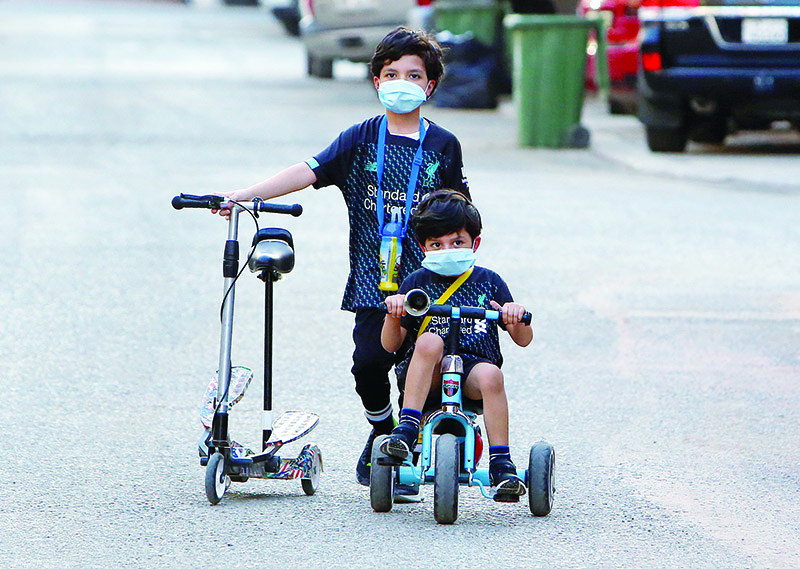 Kuwaiti children, wearing protective facemasks due to the coronavirus pandemic, cycle in a street in the Salwa district of Kuwait City on May 29, 2020. (Photo by YASSER AL-ZAYYAT / AFP)