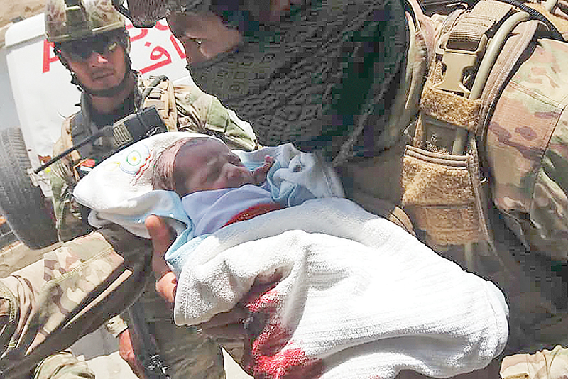 KABUL: An Afghan security personnel carries a newborn baby from a hospital, at the site of an attack in Kabul. Gunmen stormed a hospital on May 12 in the Afghan capital Kabul. — AFP