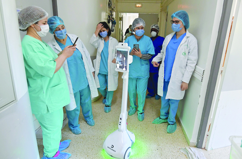 The medical staff at the Mami hospital interact with a robot, manufactured by a Tunisian company and donated to the hospital to support their efforts in combatting the coronavirus (COVID-19) pandemic, in a hallway in the hospital in the city of Ariana north of the Tunisian capital Tunis, on May 1, 2020. (Photo by FETHI BELAID / AFP)