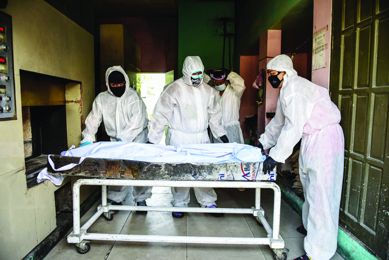 TOPSHOT - Personnel in protective suits, used due to the COVID-19 coronavirus outbreak, prepare to move a body inside the crematory chambers at a crematorium facility in Manila on April 29, 2020. - Most of the Philippines is under quarantine to contain the spread of the coronavirus that has infected over 7,000 people and killed at least 500 in the country. (Photo by Maria TAN / AFP)